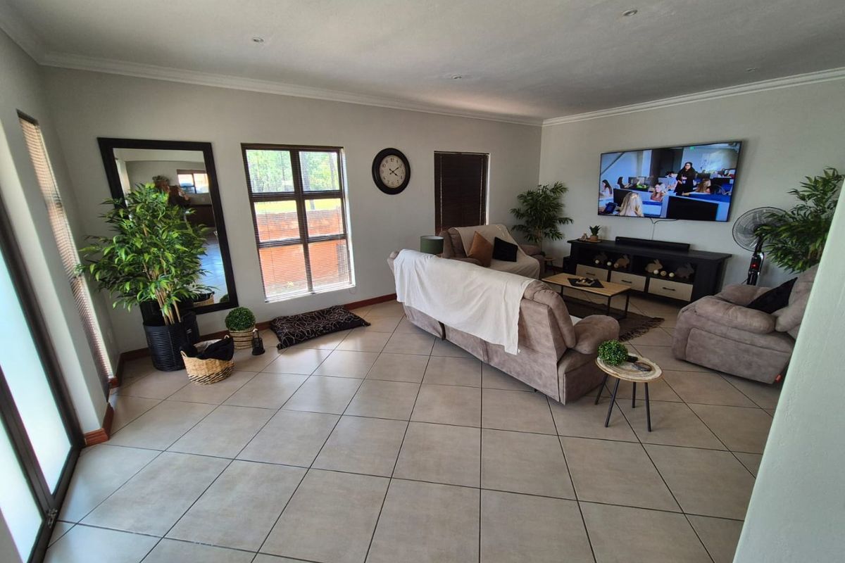 Spacious living room featuring neutral tiled flooring, recessed downlighting, and large windows providing ample natural light.
