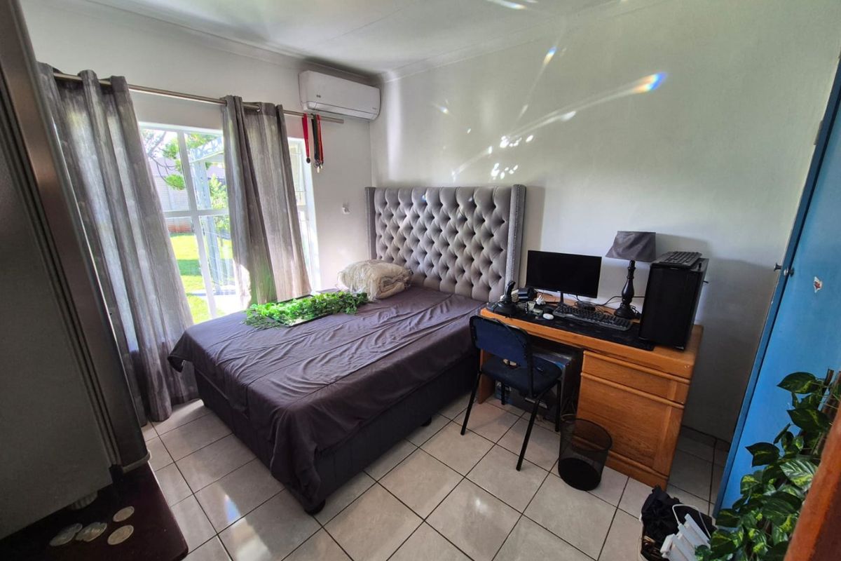 A functional bedroom featuring tiled flooring, an integrated air conditioning unit, and a sliding glass door providing access to the exterior.