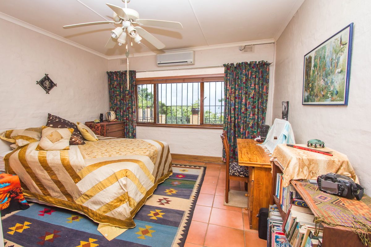 A bedroom featuring tiled flooring, a ceiling fan, and a wall-mounted split-system air conditioner, with security bars installed on the window.