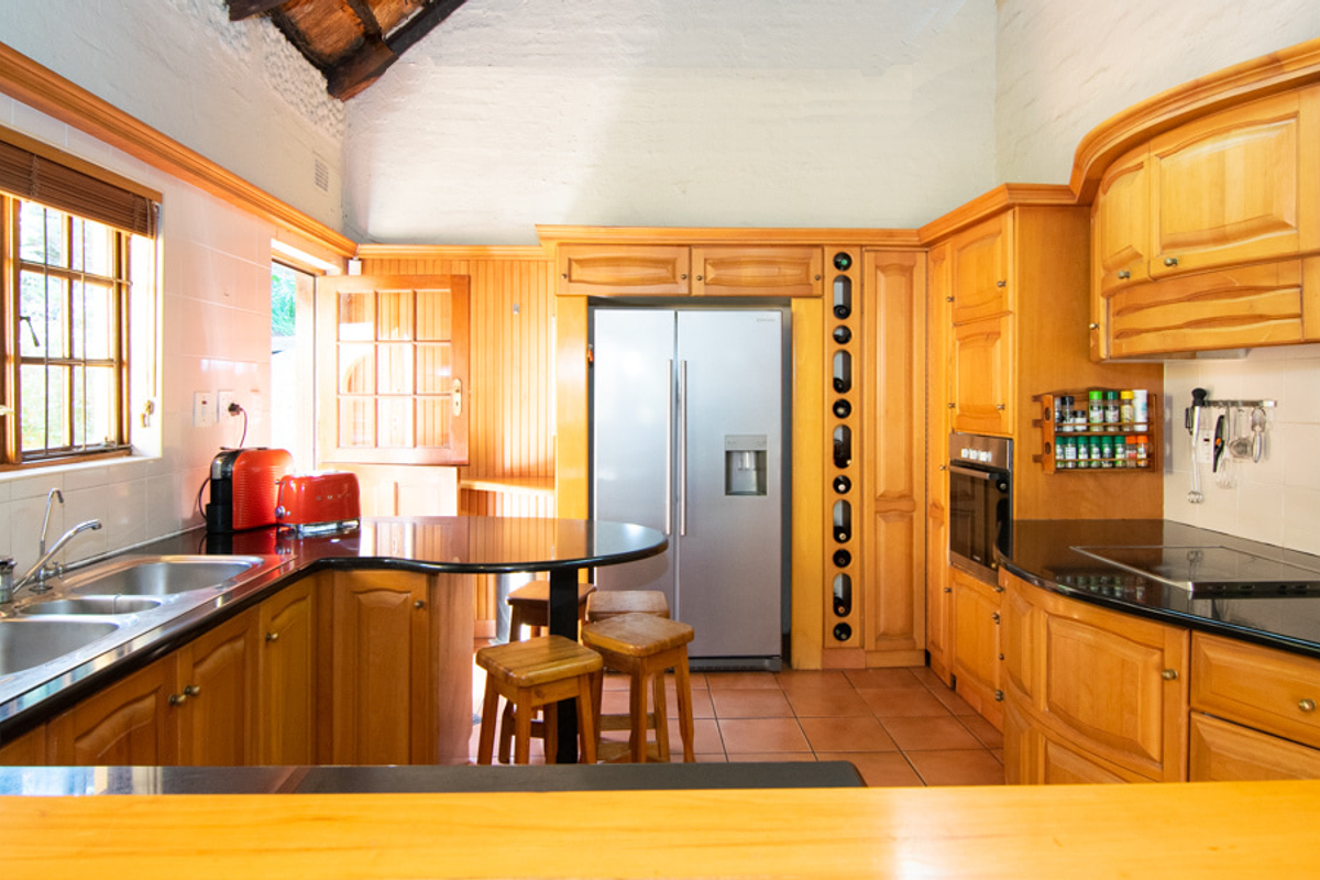 A traditional kitchen featuring warm wooden cabinetry, granite countertops, a built-in oven, electric hob, and a unique wine rack integrated into the cabinetry.