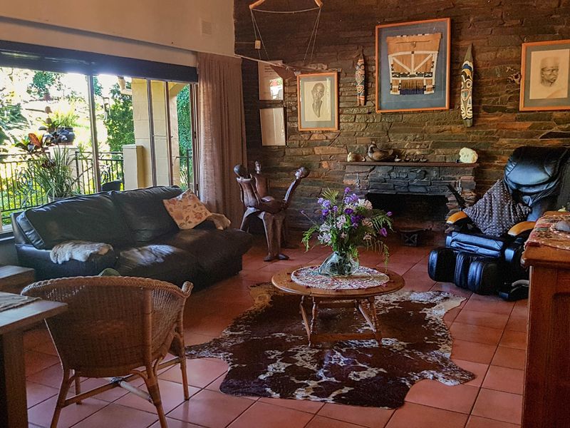 Spacious living room featuring a rustic stone fireplace, terracotta floor tiles, and large sliding glass doors providing access to the outdoor area.