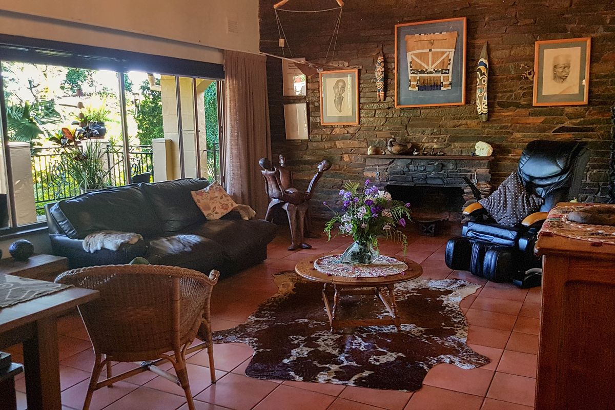 Spacious living room featuring a rustic stone fireplace, terracotta floor tiles, and large sliding glass doors providing access to the outdoor area.