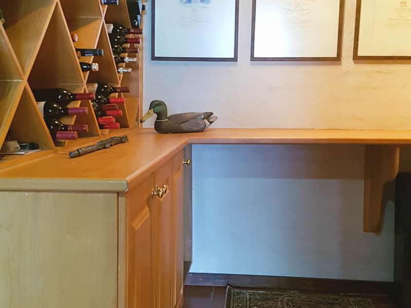 A dedicated wine cellar featuring custom built-in wooden wine racking and cabinetry with tiled flooring.