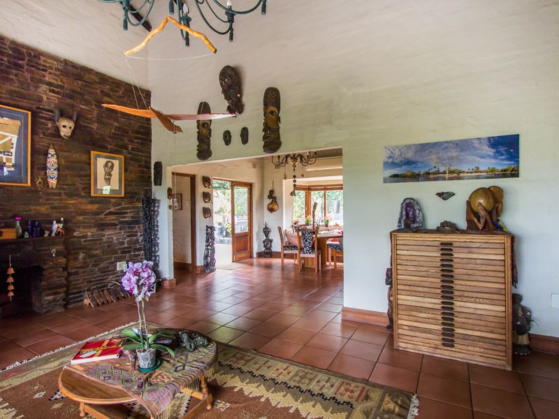 Spacious open-plan living area featuring a prominent exposed brick fireplace, vaulted ceilings, and terracotta floor tiles, with a seamless flow to the dining space.