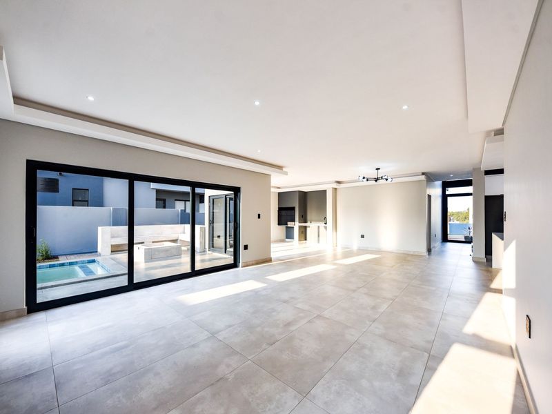 Spacious open-plan living area featuring large format floor tiles, recessed lighting, and seamless access to the outdoor patio and pool area.