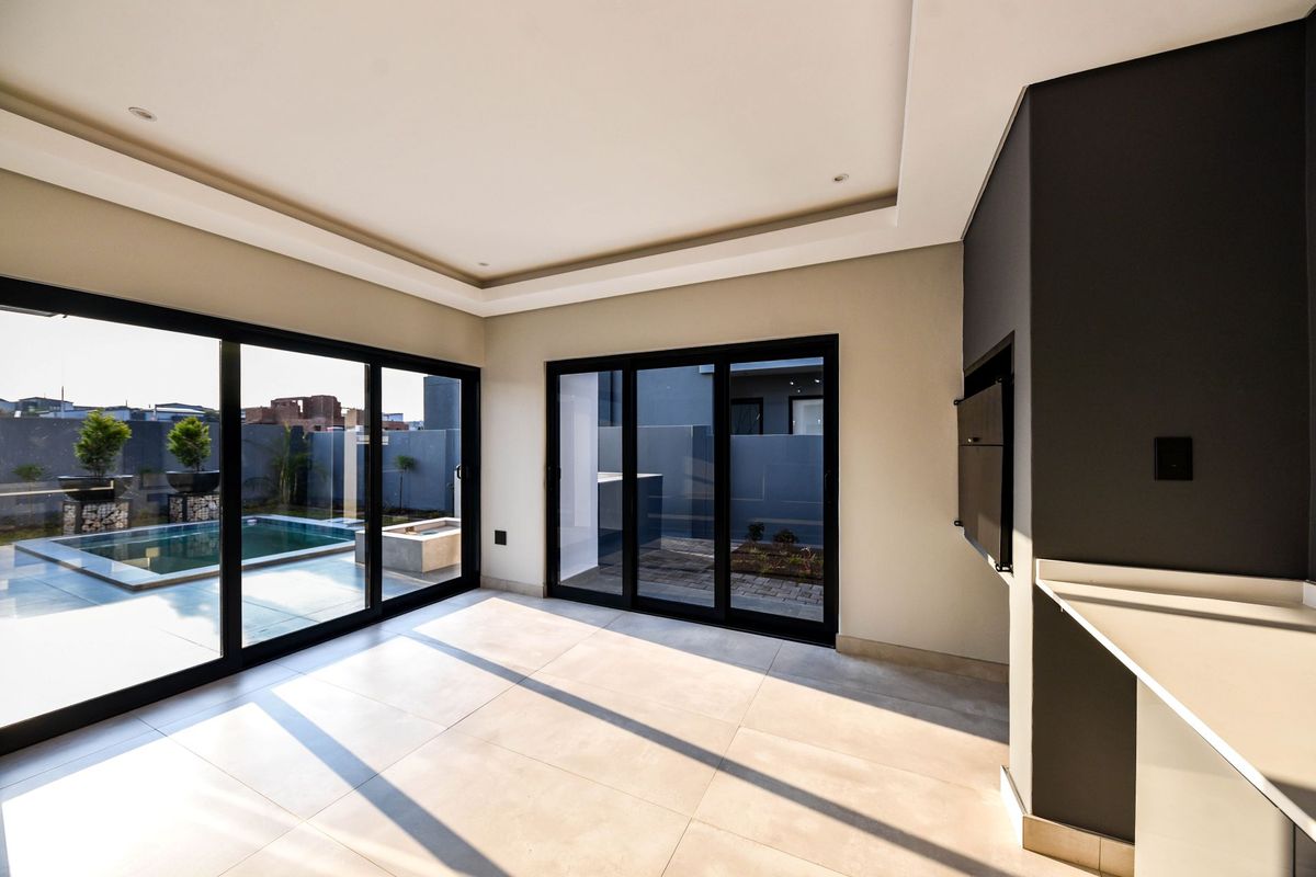 Spacious living area featuring modern tiled floors, recessed ceiling lighting, and large sliding doors opening to a private pool and patio area.