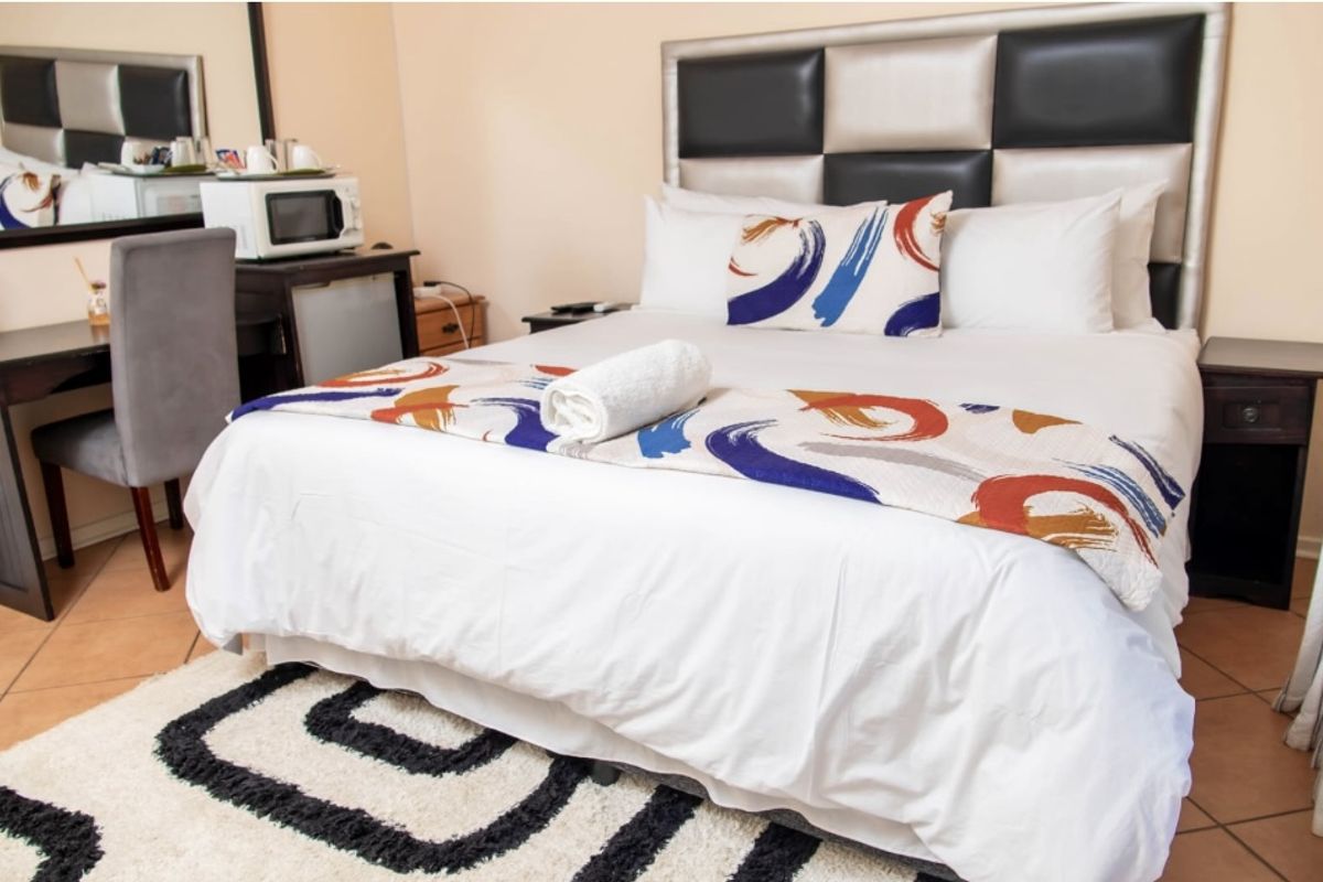 A well-maintained guest bedroom featuring tiled flooring, a built-in headboard, and a functional layout suitable for guest accommodation.