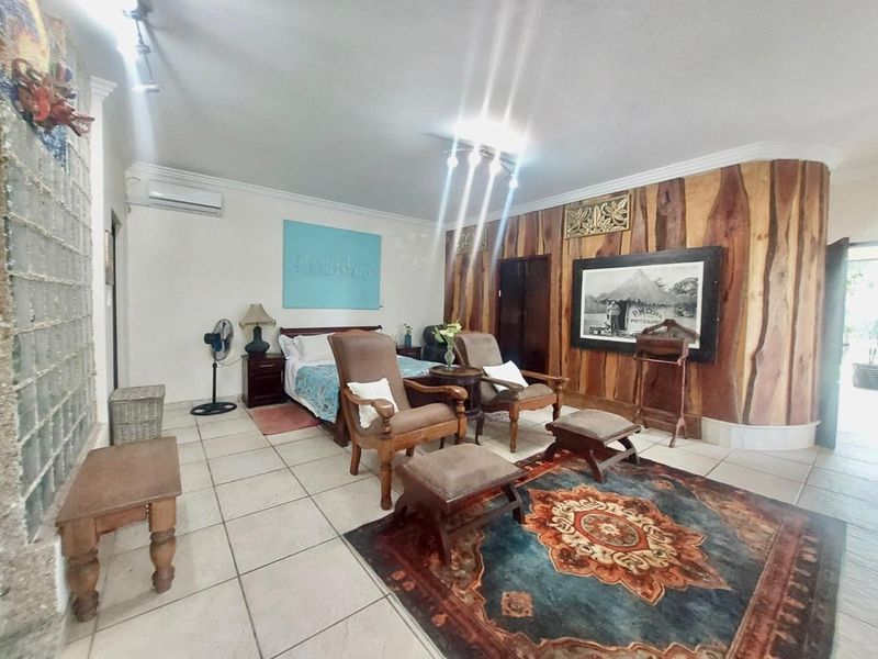 Spacious bedroom featuring tiled flooring, a wood panel feature wall, glass block accents, and a wall-mounted split-system air conditioner.