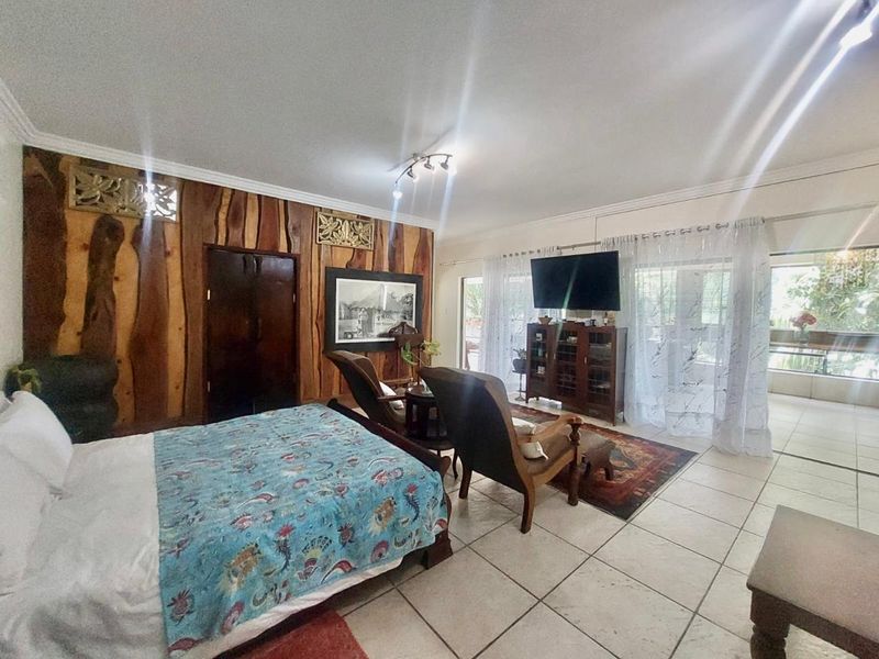 Spacious bedroom featuring unique wood paneling, tiled flooring, and large sliding glass doors that provide access to an outdoor area.