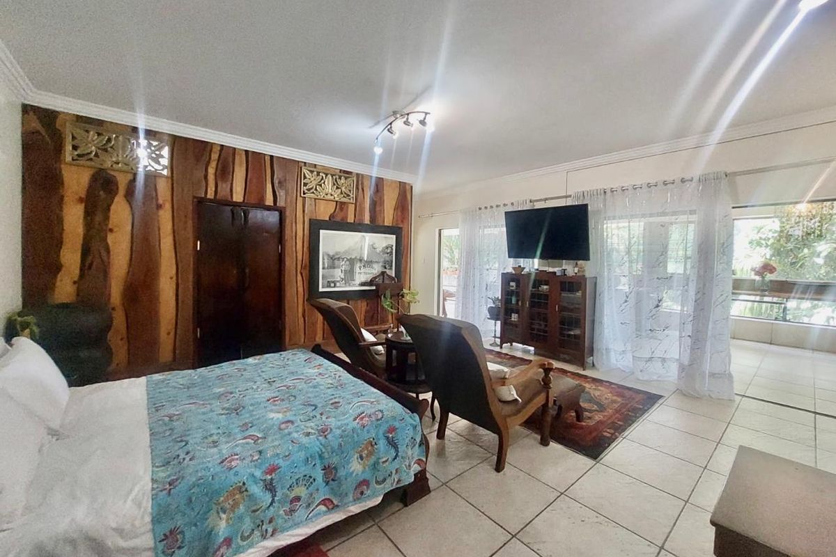 Spacious bedroom featuring unique wood paneling, tiled flooring, and large sliding glass doors that provide access to an outdoor area.