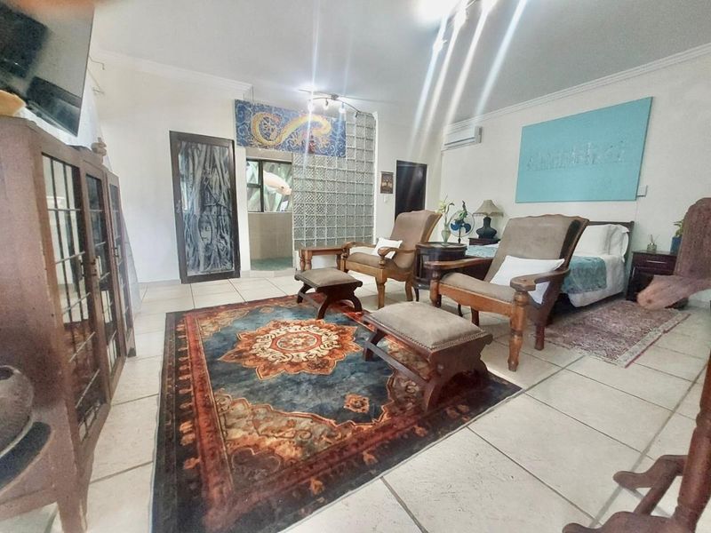 Open-plan living and bedroom area featuring ceramic floor tiles, a glass block partition wall, and a wall-mounted split-system air conditioner.