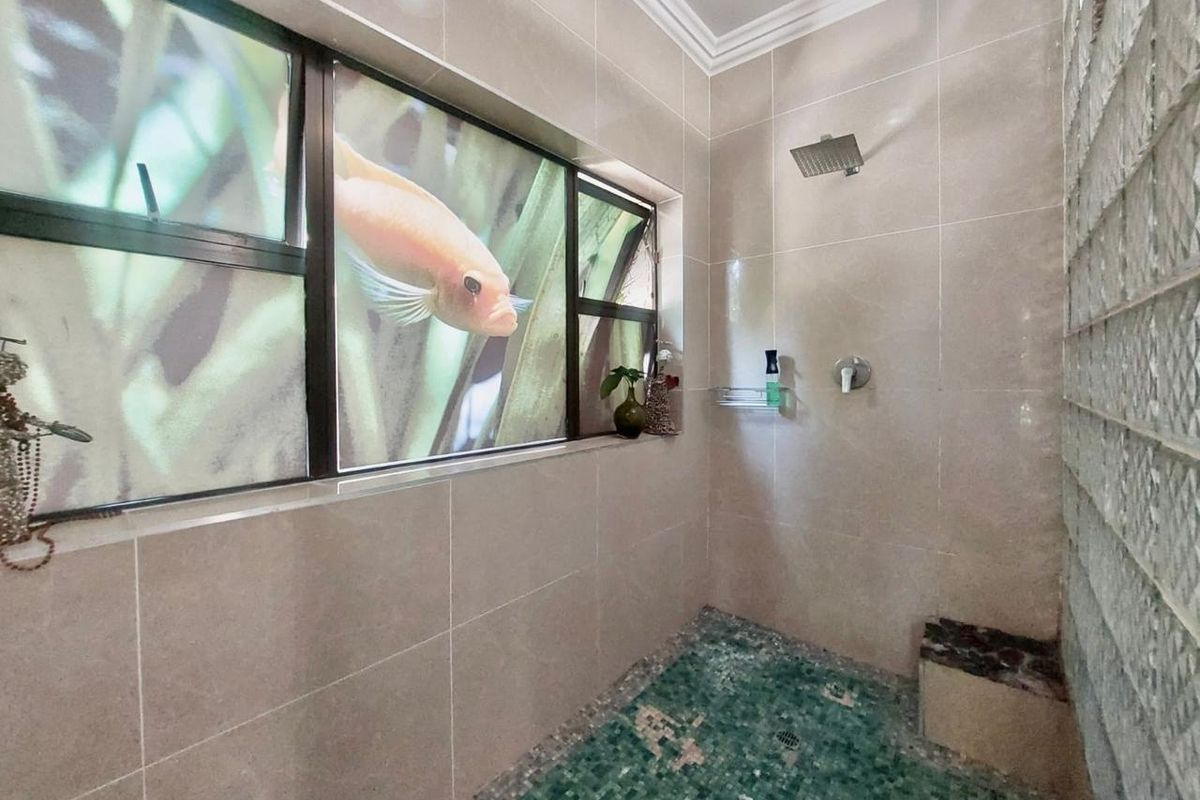 A modern walk-in shower featuring a rain shower head, mosaic tile flooring, and a unique glass block wall with a built-in bench.