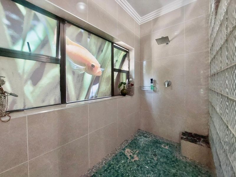 A modern walk-in shower featuring a rain shower head, mosaic tile flooring, and a unique glass block wall with a built-in bench.