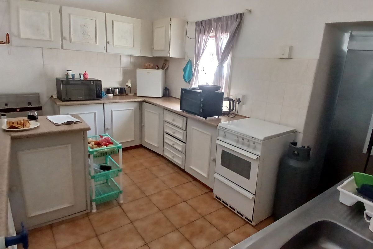 A functional kitchen featuring white cabinetry, tiled flooring, and a freestanding stove, offering a practical layout with ample counter space.