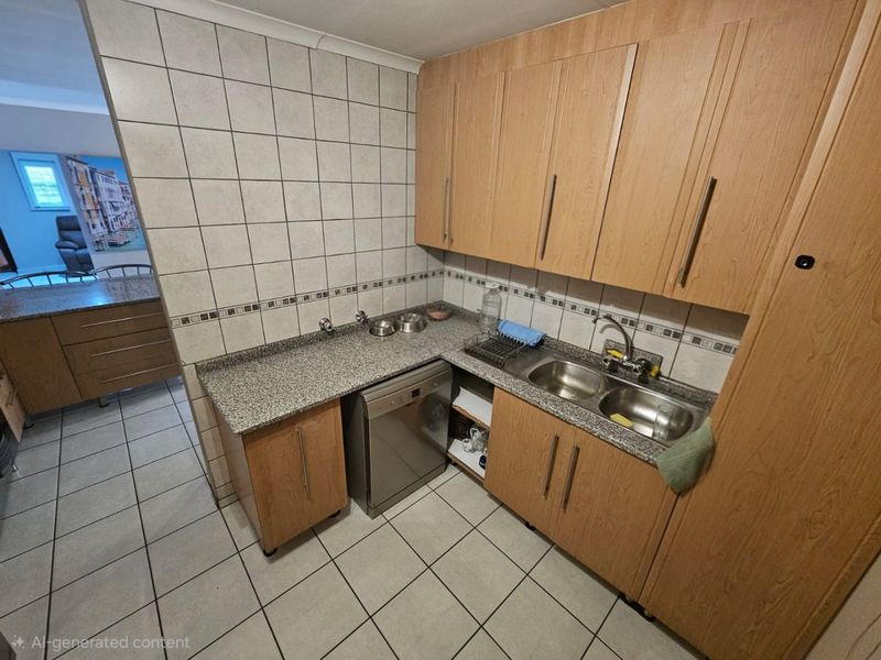 Functional scullery area featuring laminate cabinetry, granite countertops, a double bowl stainless steel sink, and tiled finishes throughout.