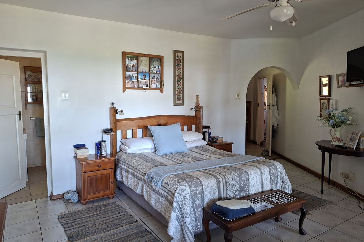 Spacious bedroom featuring tiled flooring, a ceiling fan, and an arched doorway leading to an en-suite bathroom.