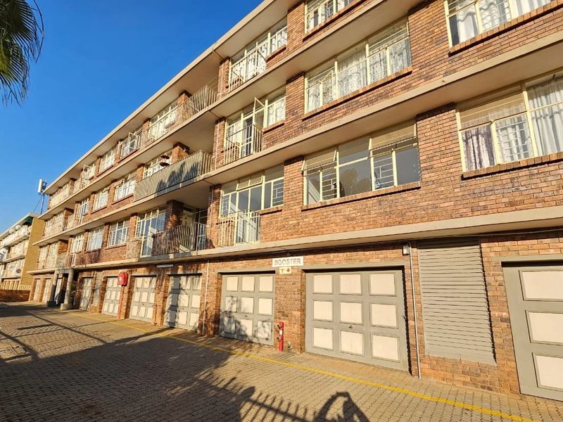 Exterior view of a multi-story apartment building featuring face brick construction, ground-level garages, and private balconies for each unit.
