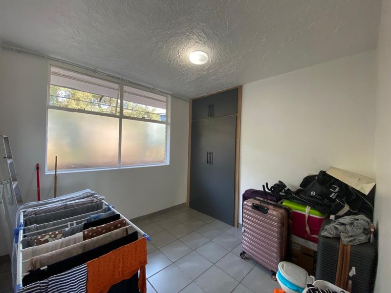 A functional laundry room featuring tiled flooring, built-in storage cupboards, and a large window providing natural light.