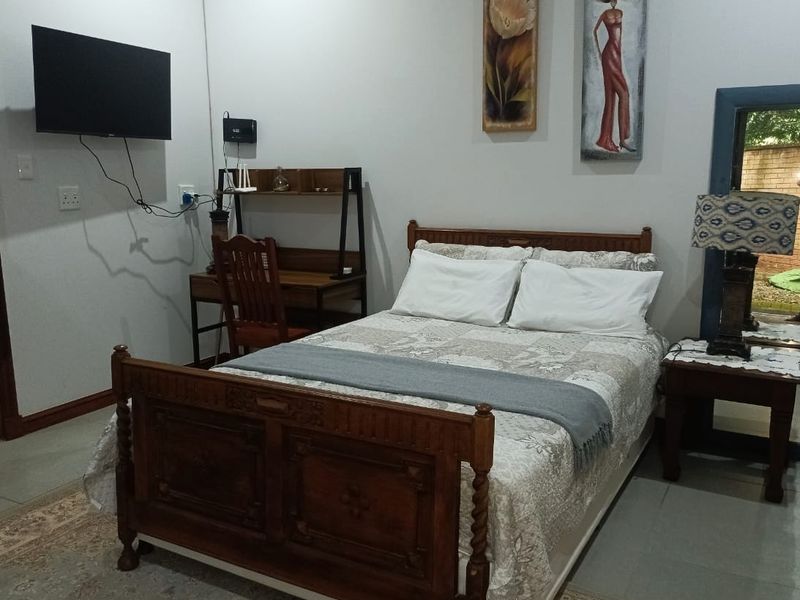 A functional bedroom featuring tiled flooring and a wall-mounted television, providing a comfortable and practical living space.