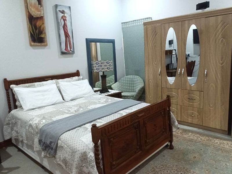 A bedroom featuring a large built-in wooden wardrobe with integrated mirrors, providing ample storage space.