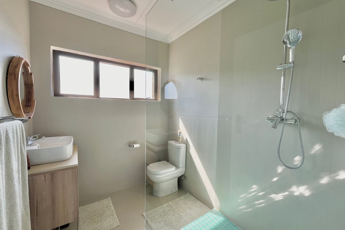 Modern bathroom featuring a vanity with vessel sink, a glass-enclosed shower with rain shower head, and neutral wall finishes.