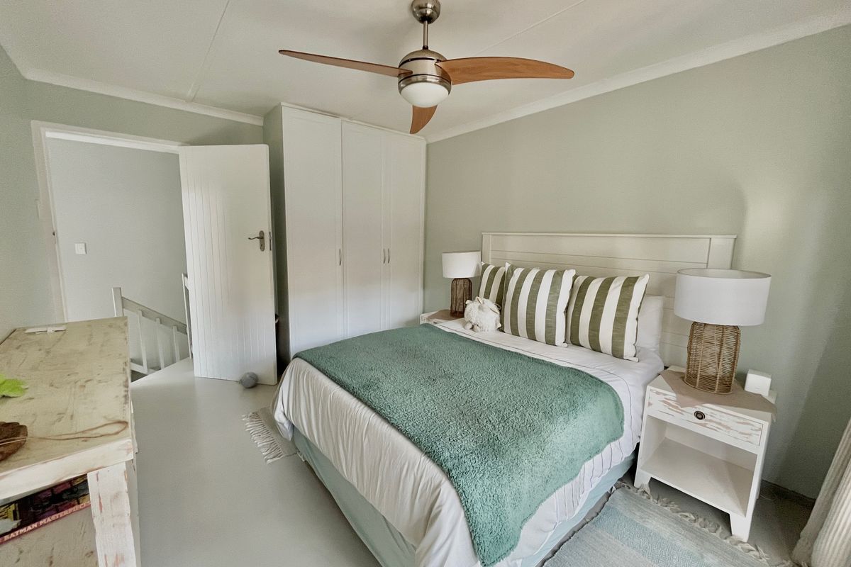 A well-lit bedroom featuring built-in cupboards, a ceiling fan, and neutral wall finishes, providing a comfortable and functional living space.
