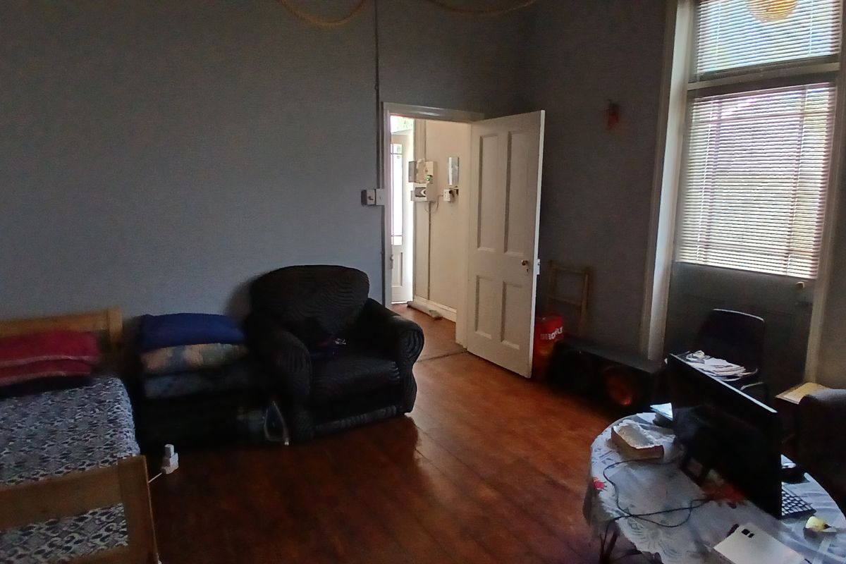 A bedroom featuring original timber flooring and a window with fitted blinds, offering a functional space with potential for cosmetic updates.