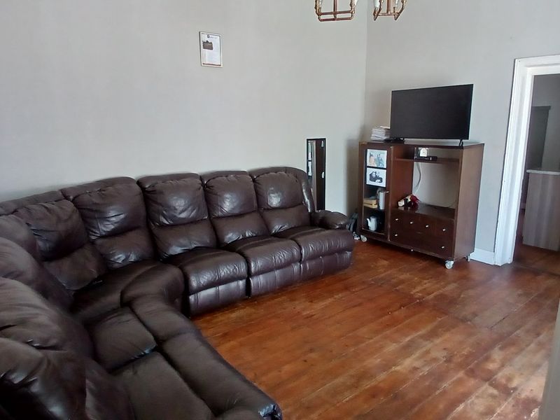 A living room featuring original hardwood flooring and neutral wall tones, offering a functional space ready for cosmetic updates.