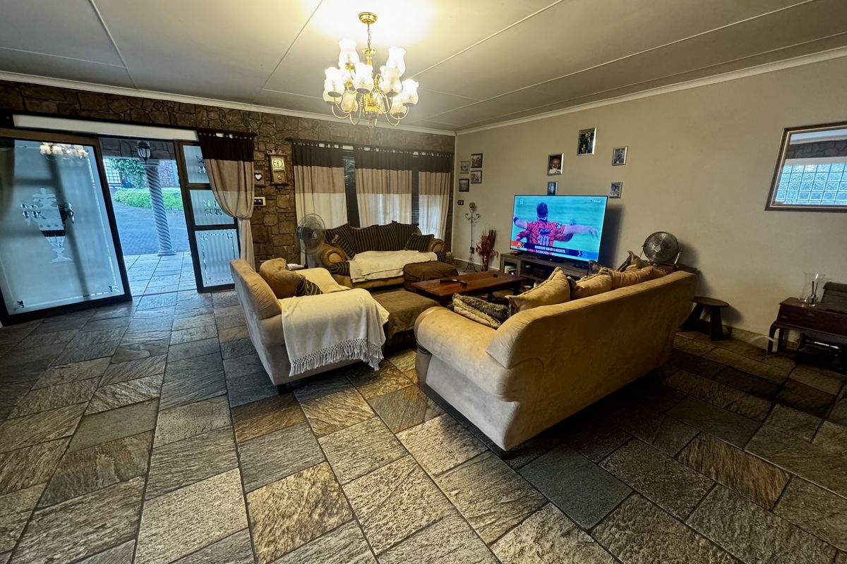 Spacious living room featuring natural stone flooring, a rustic stone feature wall, and direct access to an outdoor patio area.