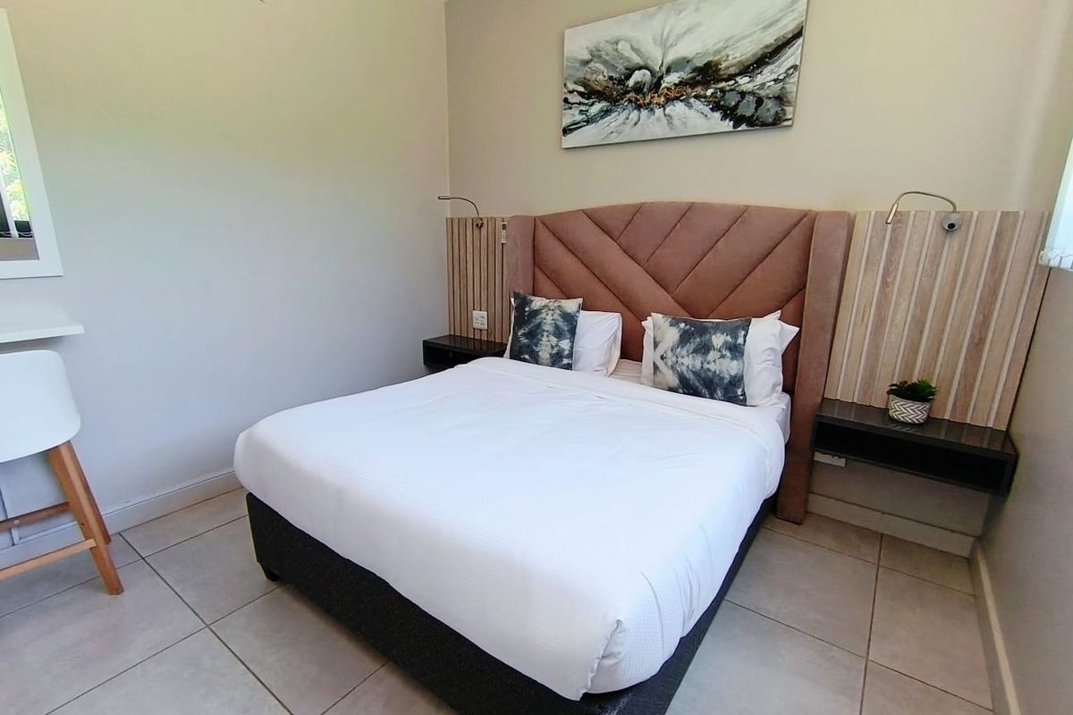 A well-maintained bedroom featuring tiled flooring, a custom built-in headboard with integrated bedside tables, and wall-mounted reading lights.
