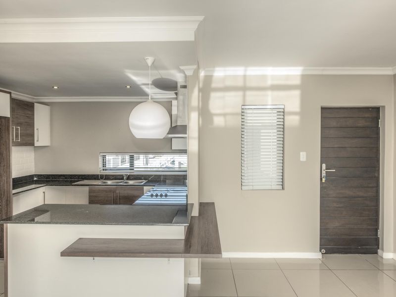 Modern open-plan kitchen featuring granite countertops, built-in cabinetry, and tiled flooring, seamlessly integrated with the living area.