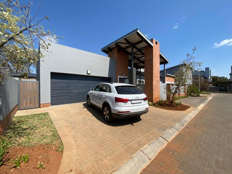 Front elevation of a modern house featuring a double garage, paved driveway, and distinctive brick and plaster architectural detailing.