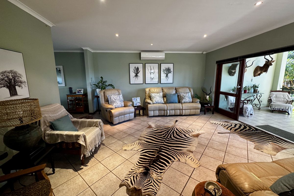 Spacious living room featuring tiled flooring, recessed downlighting, and a wall-mounted air conditioning unit, with direct access to an outdoor patio area.