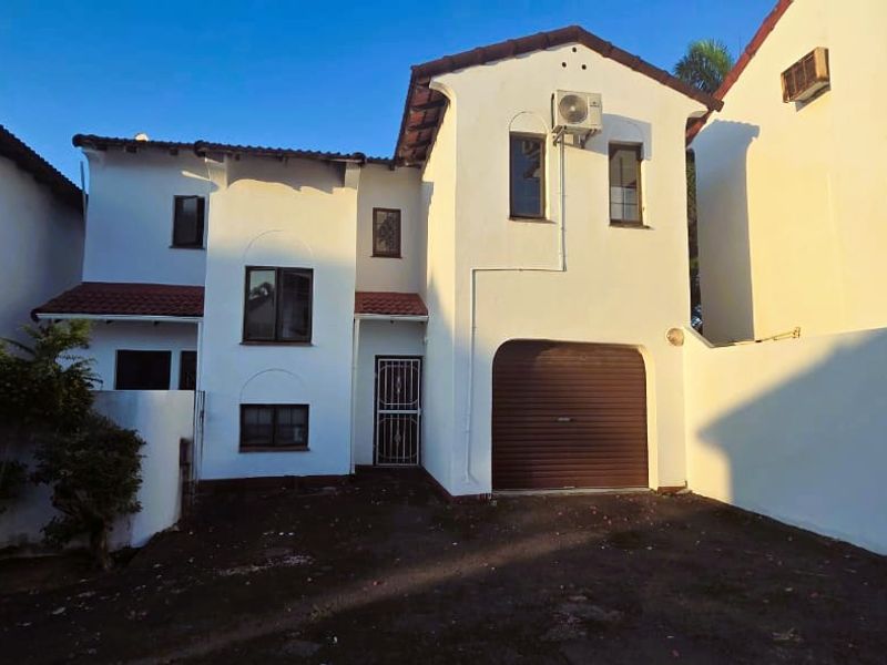 Front elevation of a townhouse featuring a single garage, tiled roof, and exterior wall finishes.