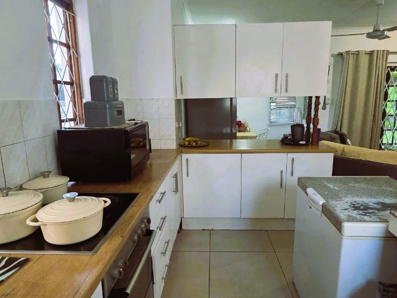 A functional kitchen featuring white cabinetry, laminate countertops, and tiled backsplash, offering a practical layout with integrated cooking appliances.
