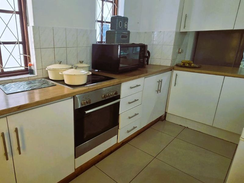 Functional kitchen featuring built-in oven, electric hob, tiled backsplash, and ample cabinetry with laminate countertops.