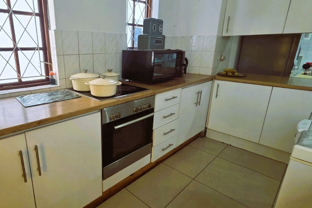 Functional kitchen featuring built-in oven, electric hob, tiled backsplash, and ample cabinetry with laminate countertops.