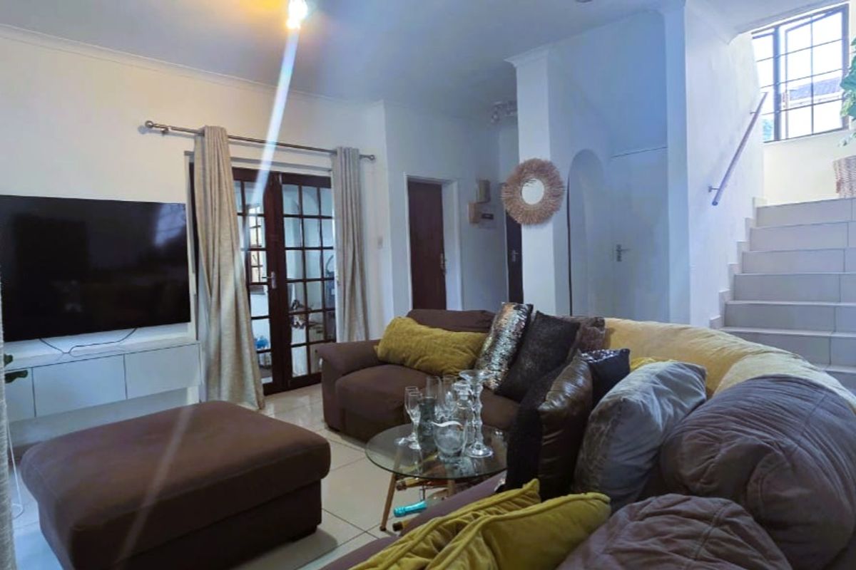 A comfortable living room featuring tiled flooring, a staircase leading to the upper level, and classic french doors providing natural light.
