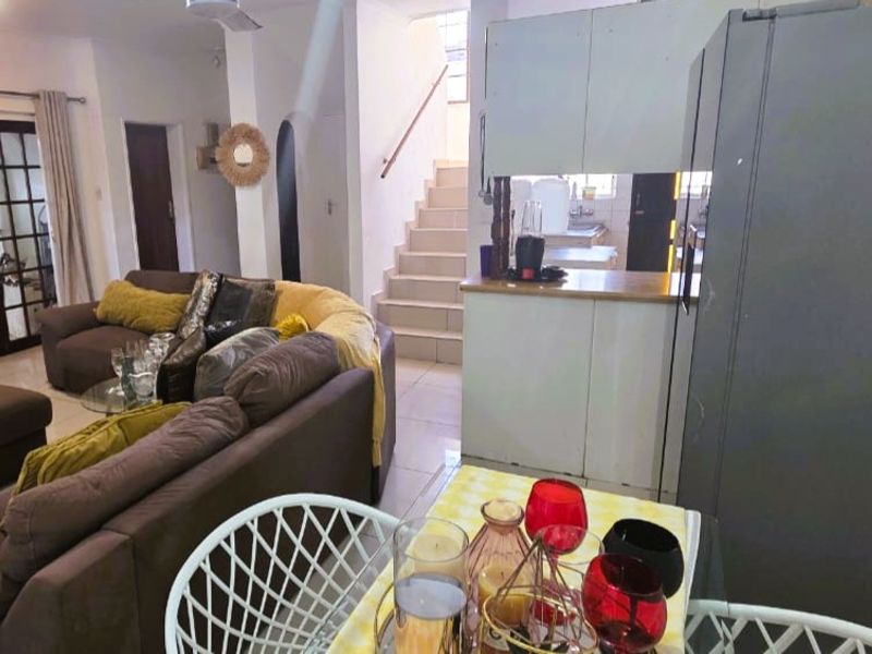 Open plan living and dining area featuring tiled floors, a staircase with a wooden handrail, and access to the exterior via french doors.