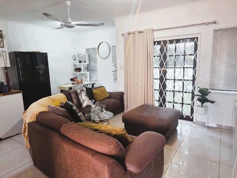 Open plan living area featuring tiled flooring, a ceiling fan, and direct access to the exterior through a secure glass door.