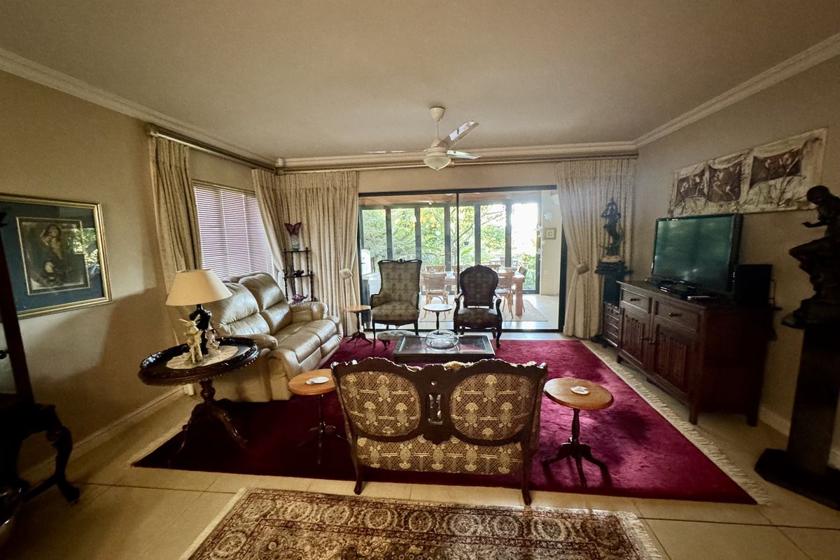 Spacious living room featuring tiled flooring, crown molding, a ceiling fan, and large sliding glass doors providing access to the outdoor patio area.