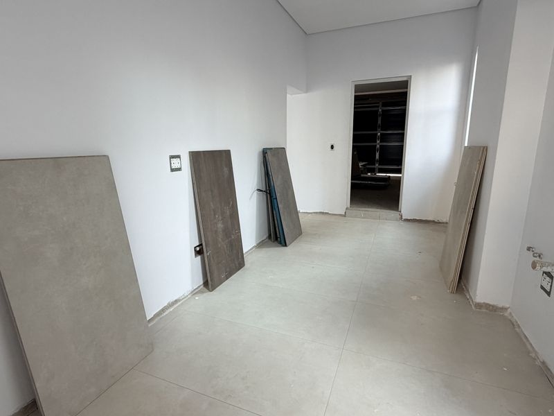 An unfinished kitchen space featuring tiled flooring, exposed plumbing connections, and electrical outlets, ready for cabinetry and appliance installation.