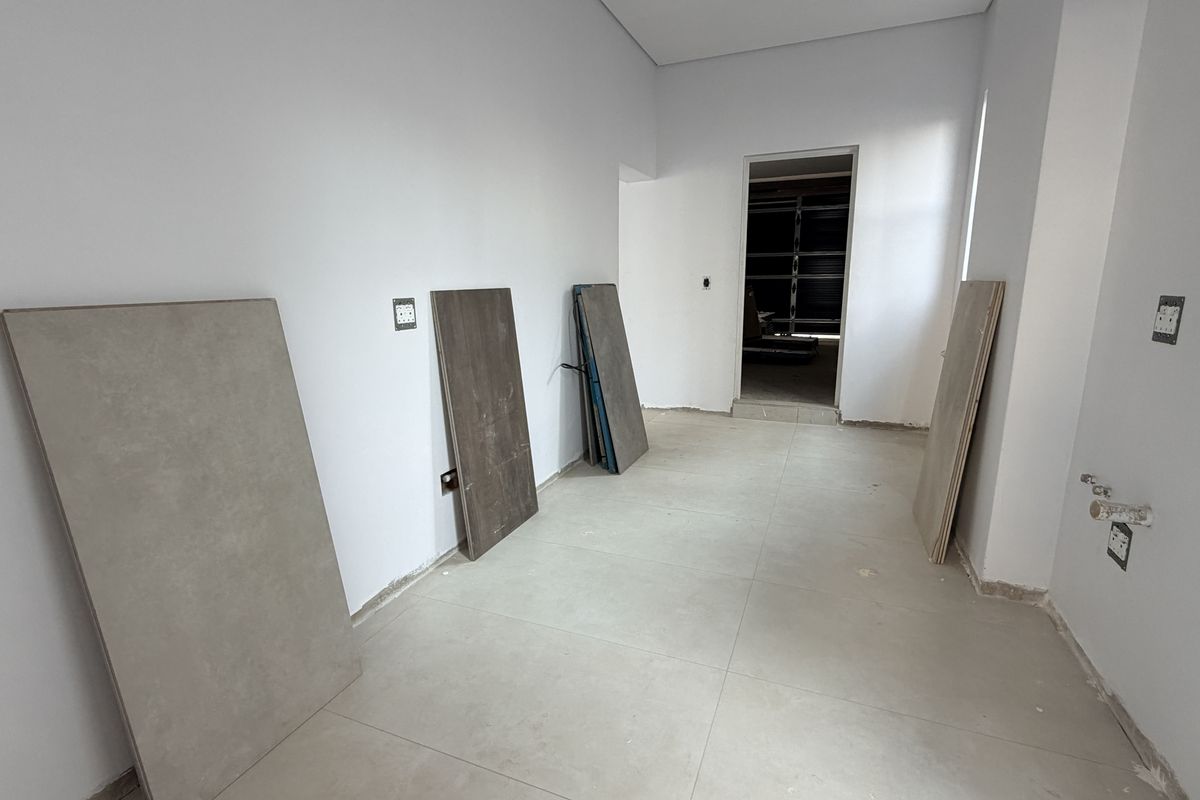 An unfinished kitchen space featuring tiled flooring, exposed plumbing connections, and electrical outlets, ready for cabinetry and appliance installation.