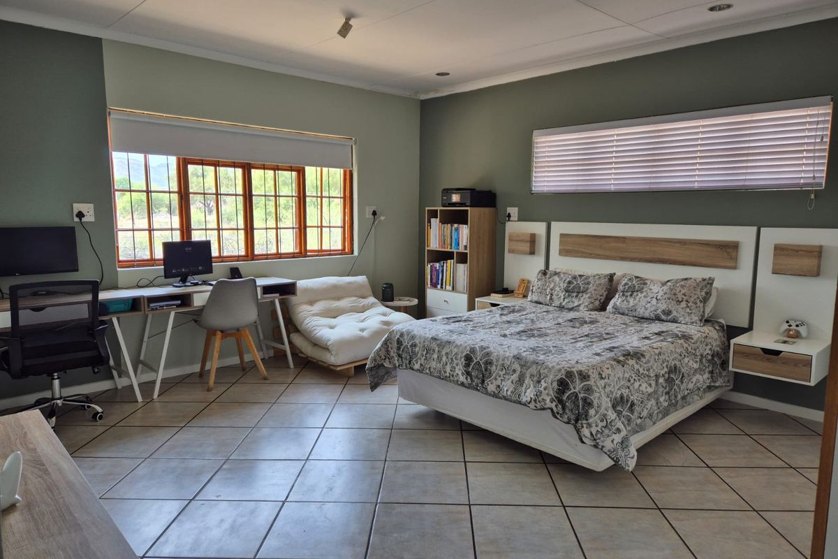 Spacious bedroom featuring tiled flooring, built-in headboard with integrated bedside tables, and large windows providing natural light.
