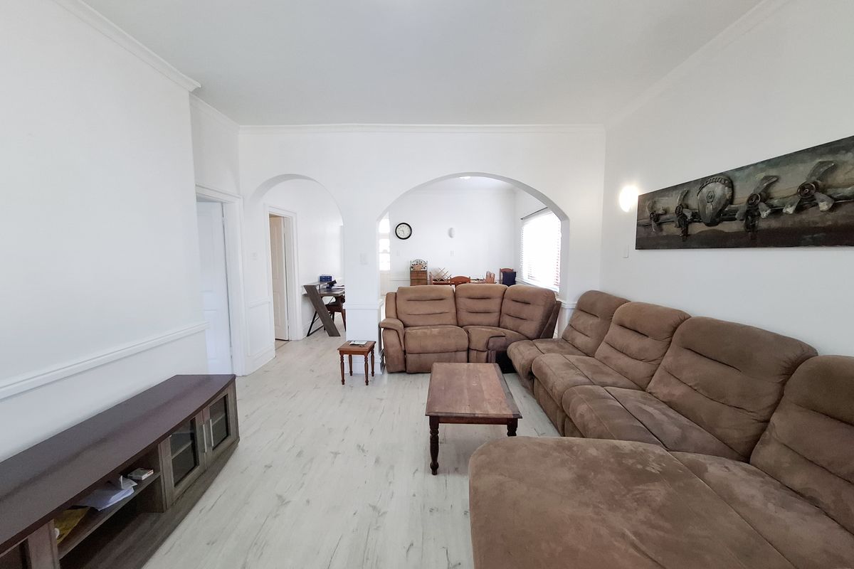 Spacious living room featuring light-toned laminate flooring, decorative archways, and classic coving, creating an open and inviting atmosphere.