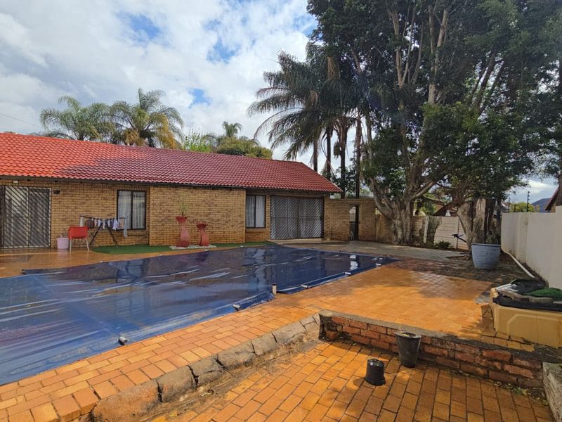 Outdoor pool area featuring a covered swimming pool, brick paving, and a face brick house exterior with a tiled roof.
