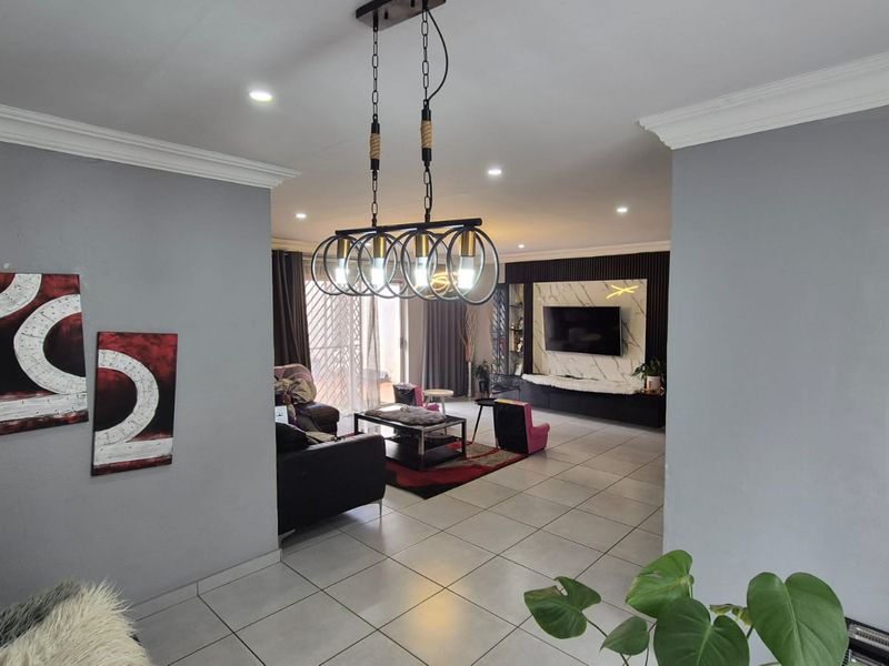 Spacious living area featuring tiled floors, recessed lighting, crown molding, and a modern feature wall with a built-in media console.