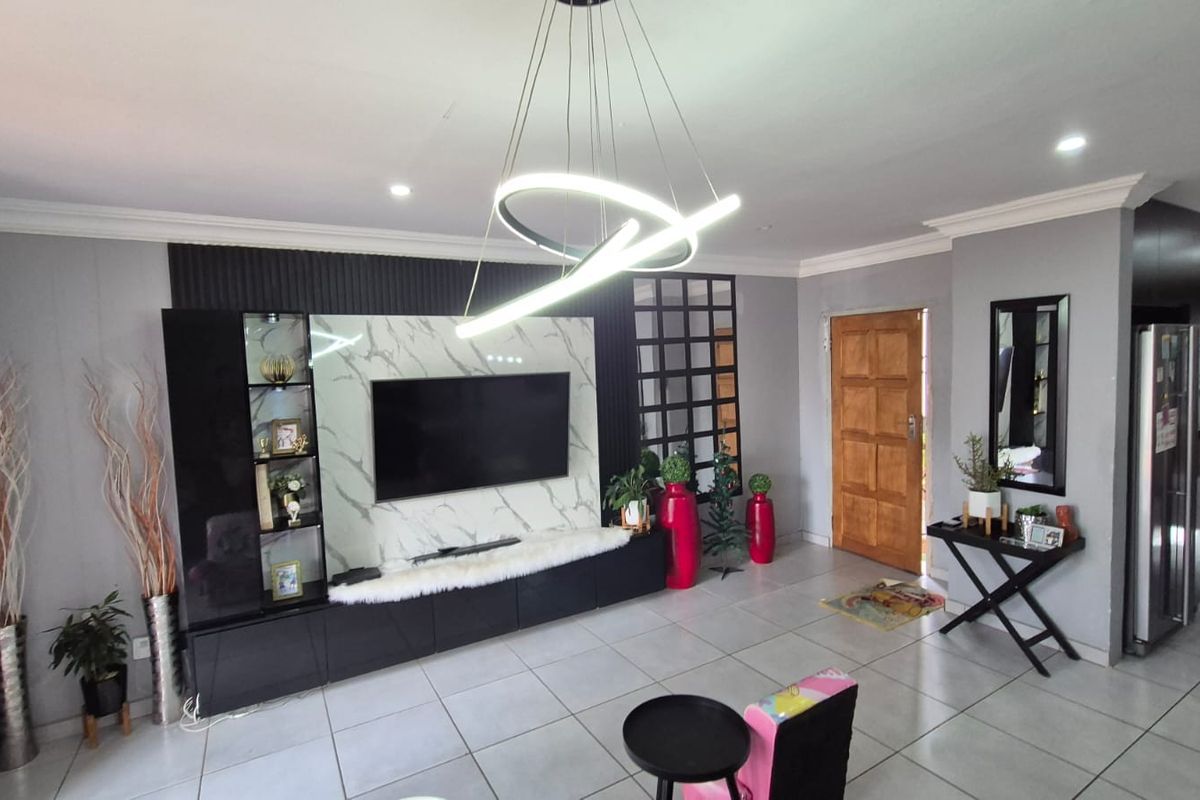 A modern living room featuring a marble-effect media wall, built-in cabinetry, contemporary pendant lighting, and neutral tiled flooring.