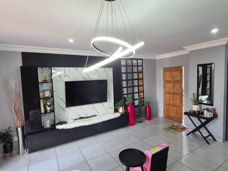 A modern living room featuring a marble-effect media wall, built-in cabinetry, contemporary pendant lighting, and neutral tiled flooring.