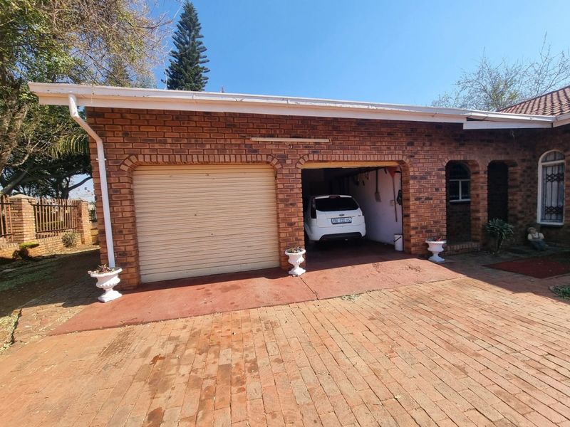 A double garage featuring a face brick exterior, one roller shutter door, and a paved driveway entrance.